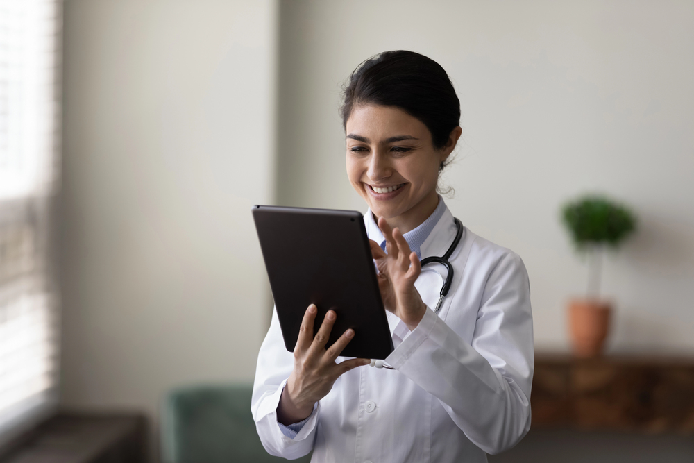 A doctor reviewing information on a tablet in a naturally lit workspace